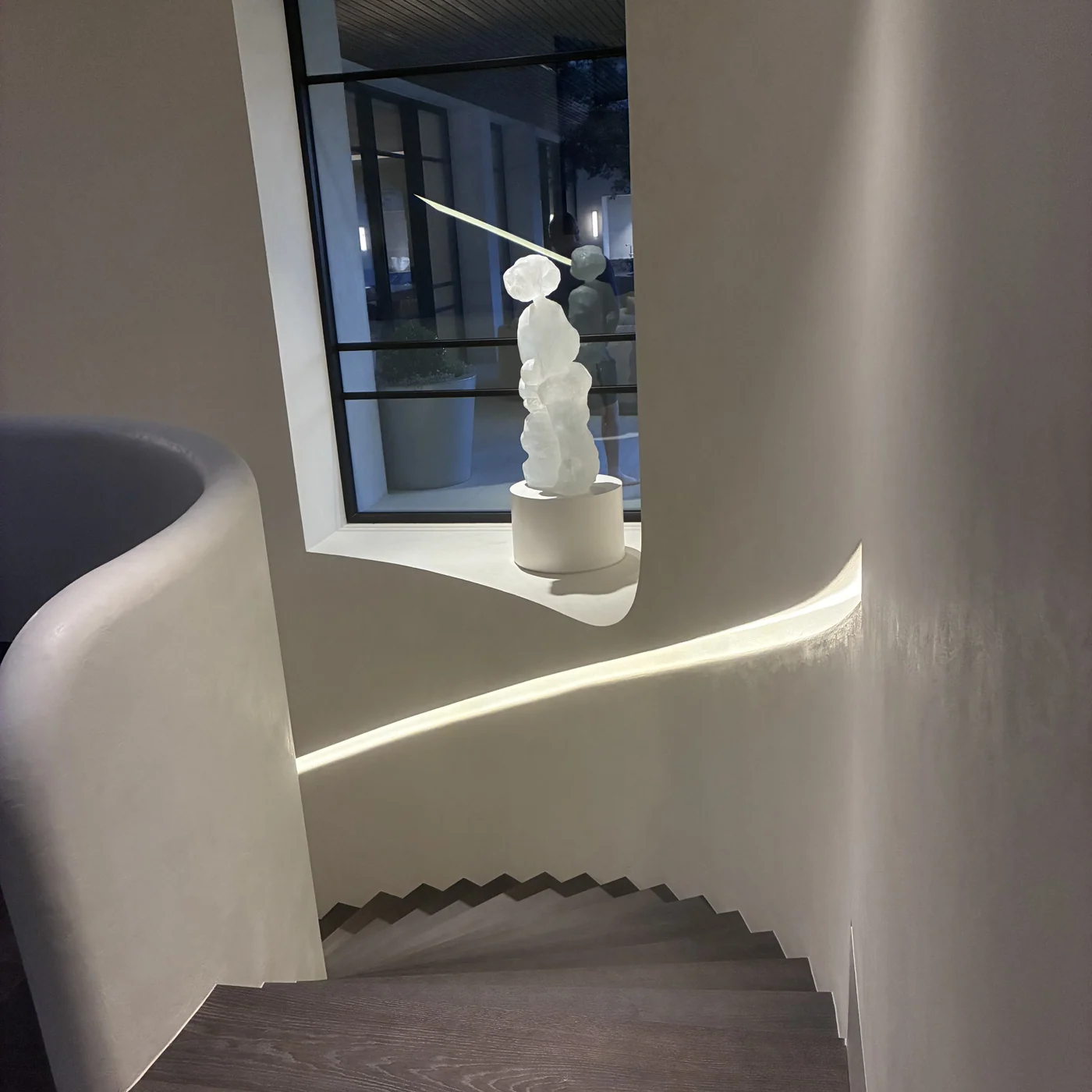 Curved plaster stairwell with a sculpted niche and cove lighting