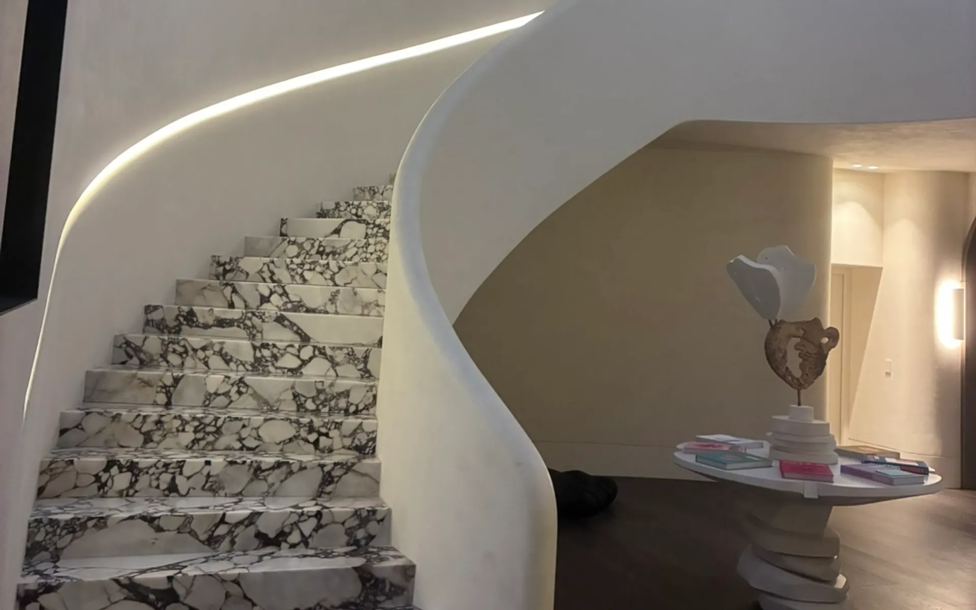 Sculptural curved staircase with marble treads, custom carpentry by Pears Building Concepts