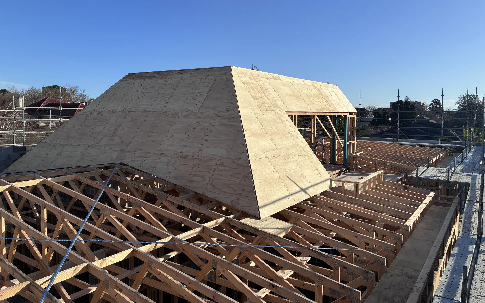 Timber roof framing against a blue sky