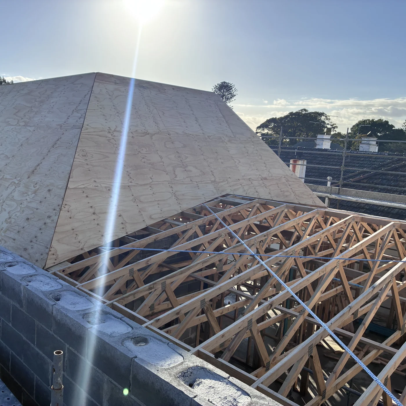 Timber roof framing and trusses against a blue sky