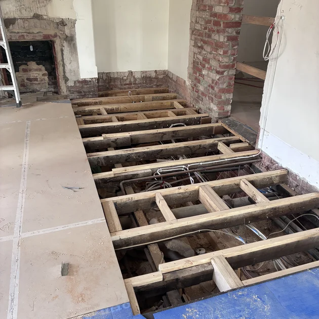 Subfloor joists being replaced beside an original fireplace during a home renovation